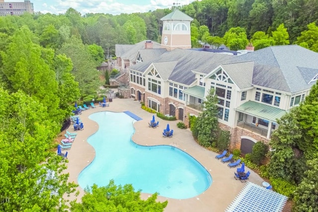 community pool with a patio and a view of trees