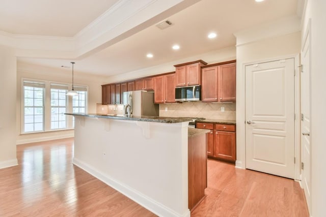 kitchen featuring appliances with stainless steel finishes, brown cabinets, a breakfast bar, tasteful backsplash, and light wood-style flooring