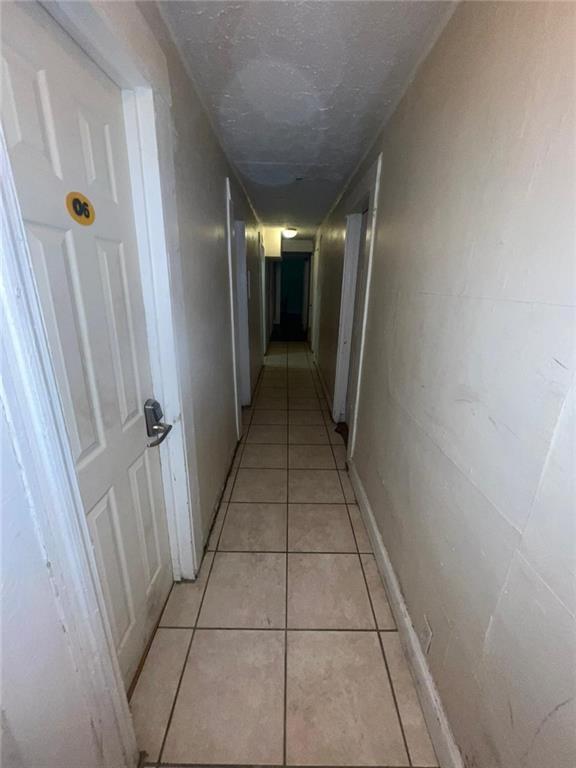 corridor featuring light tile patterned flooring and a textured ceiling