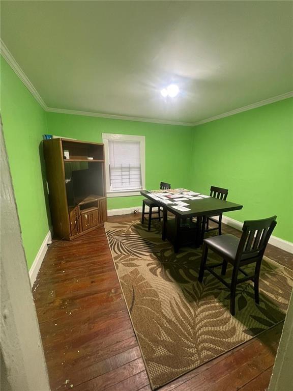 dining space with dark wood-type flooring and ornamental molding