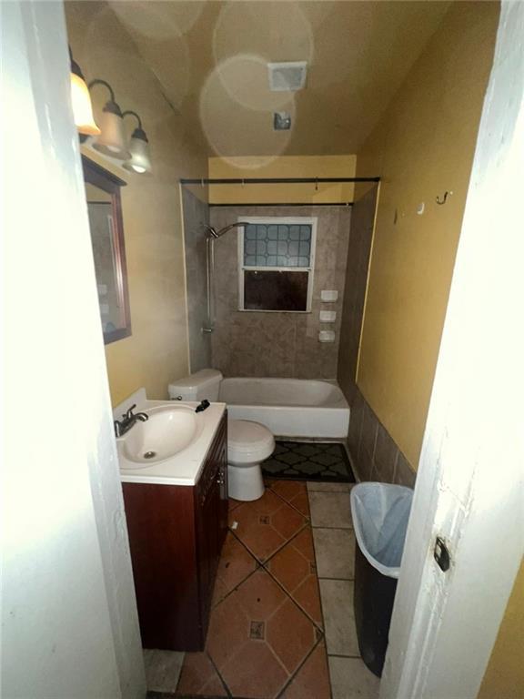 full bathroom with vanity, toilet, tiled shower / bath combo, and tile patterned flooring