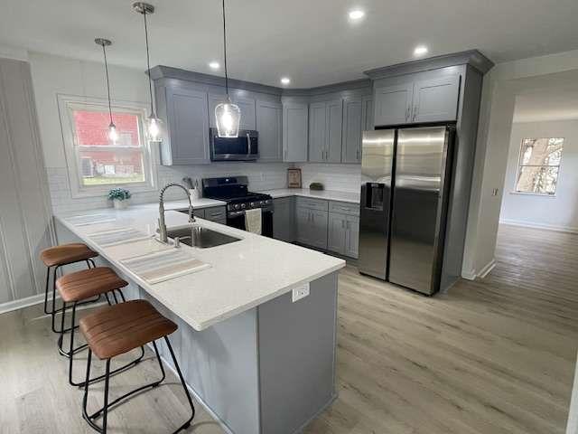 kitchen featuring decorative light fixtures, sink, stainless steel appliances, and a wealth of natural light