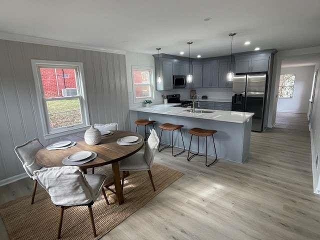 kitchen featuring sink, hanging light fixtures, appliances with stainless steel finishes, gray cabinets, and kitchen peninsula