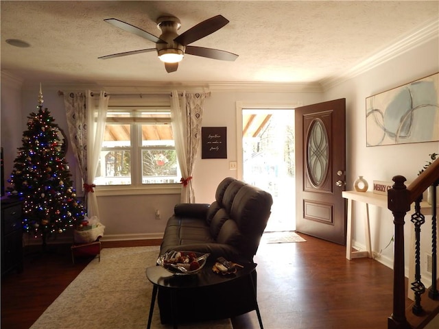 living room featuring ornamental molding, a textured ceiling, ceiling fan, and dark wood-type flooring