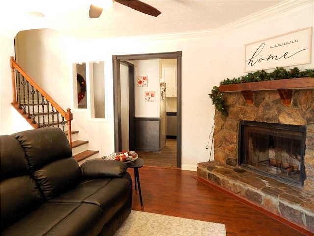 living room featuring hardwood / wood-style floors, a fireplace, ceiling fan, and crown molding