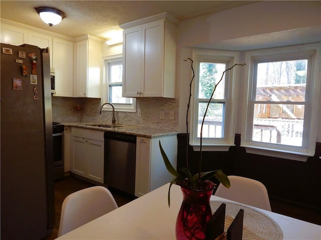 kitchen featuring white cabinets, sink, tasteful backsplash, light stone counters, and stainless steel appliances