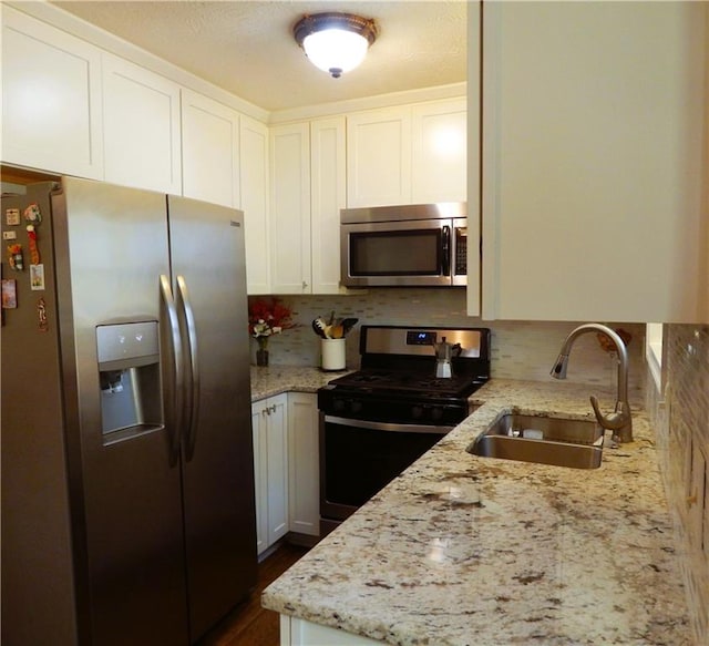 kitchen with light stone countertops, sink, white cabinetry, and stainless steel appliances