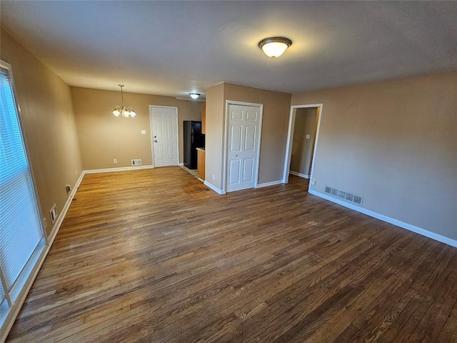 unfurnished room with a chandelier and dark hardwood / wood-style flooring