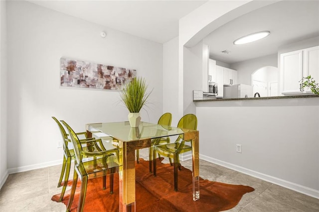 6571 Splitpine Ct, Atlanta, GA 30349 - dining space with arched walkways, baseboards, and light tile patterned flooring