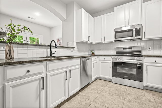 6571 Splitpine Ct, Atlanta, GA 30349 - kitchen featuring appliances with stainless steel finishes, a sink, decorative backsplash, and dark stone counters