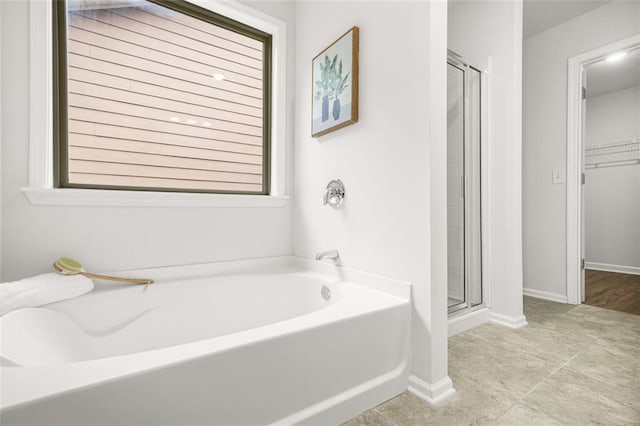 6571 Splitpine Ct, Atlanta, GA 30349 - full bathroom featuring a shower stall, a garden tub, a walk in closet, and baseboards