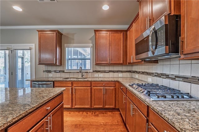 kitchen featuring decorative backsplash, stainless steel appliances, crown molding, light wood-type flooring, and a sink