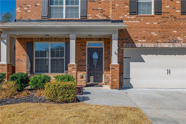 entrance to property featuring a garage, driveway, and brick siding