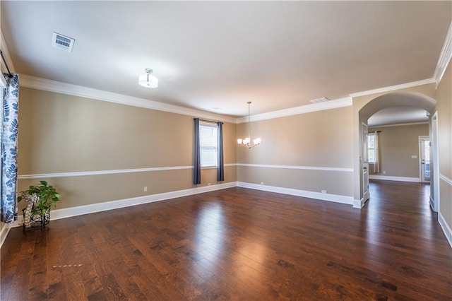 empty room featuring dark wood-style floors, arched walkways, visible vents, and baseboards