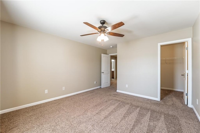 unfurnished bedroom with baseboards, ceiling fan, a spacious closet, carpet flooring, and a closet