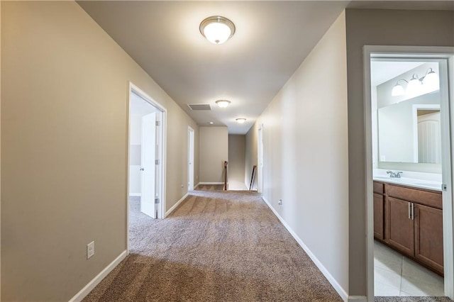 hall featuring baseboards, an upstairs landing, visible vents, and light colored carpet