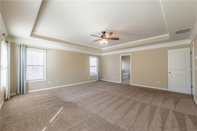 carpeted spare room featuring crown molding, a tray ceiling, visible vents, and baseboards