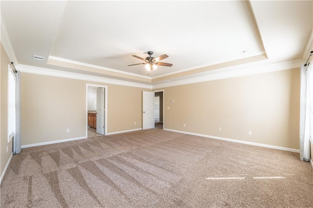 unfurnished bedroom featuring crown molding, a tray ceiling, carpet, and baseboards