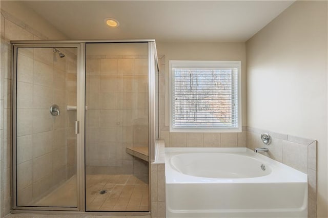 bathroom with a stall shower, a bath, and recessed lighting