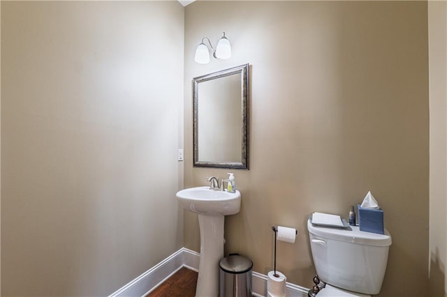 bathroom with wood finished floors, toilet, and baseboards