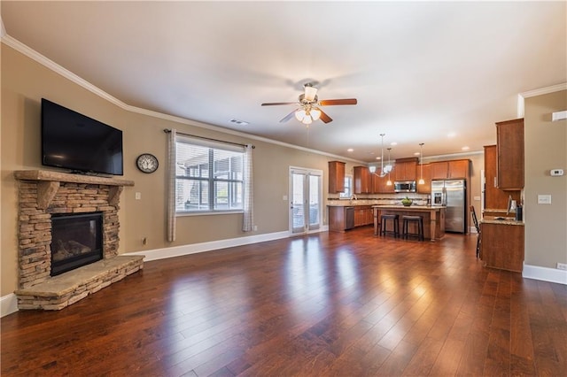 unfurnished living room with ornamental molding, dark wood-style flooring, and a stone fireplace