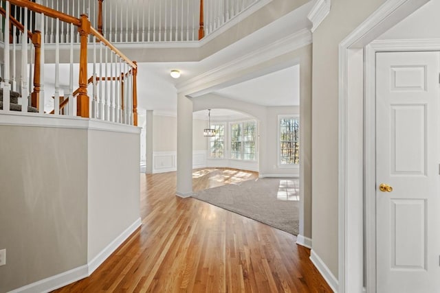 carpeted entrance foyer with ornamental molding and a notable chandelier