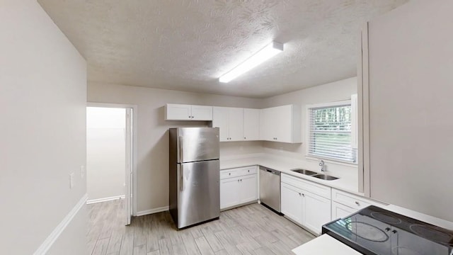 kitchen featuring appliances with stainless steel finishes, a sink, white cabinetry, light countertops, and a textured ceiling