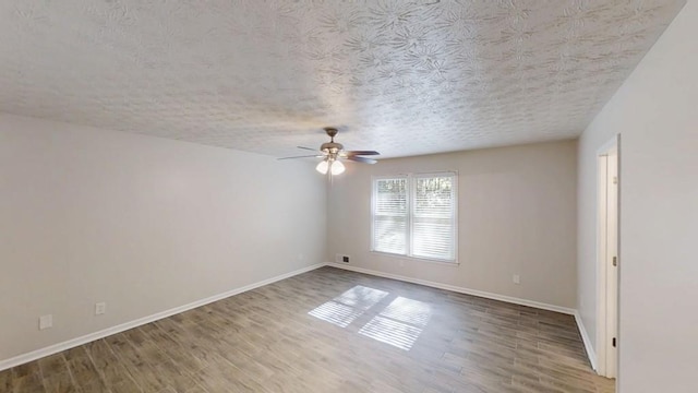 unfurnished room with ceiling fan, wood finished floors, baseboards, and a textured ceiling