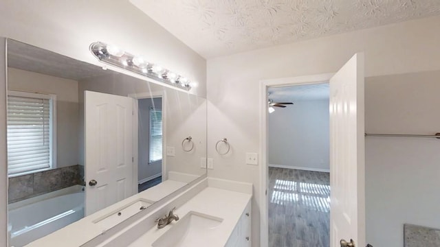 bathroom with plenty of natural light, vanity, a ceiling fan, a textured ceiling, and a garden tub