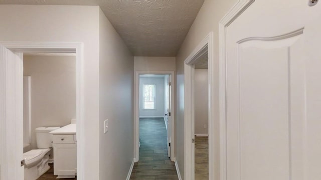 corridor with baseboards, dark wood finished floors, and a textured ceiling