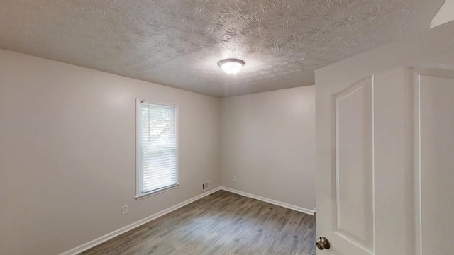 unfurnished room featuring wood finished floors, a textured ceiling, and baseboards