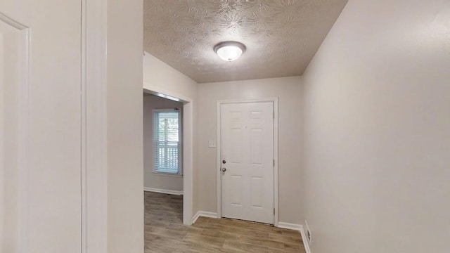 entrance foyer featuring light wood-type flooring, a textured ceiling, and baseboards
