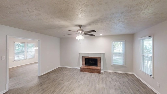 unfurnished living room featuring a textured ceiling, wood finished floors, ceiling fan, and healthy amount of natural light
