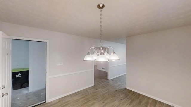 unfurnished dining area featuring a chandelier, wood finished floors, and baseboards