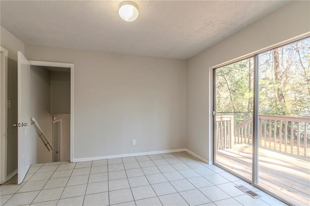 unfurnished room featuring a textured ceiling and light tile patterned floors