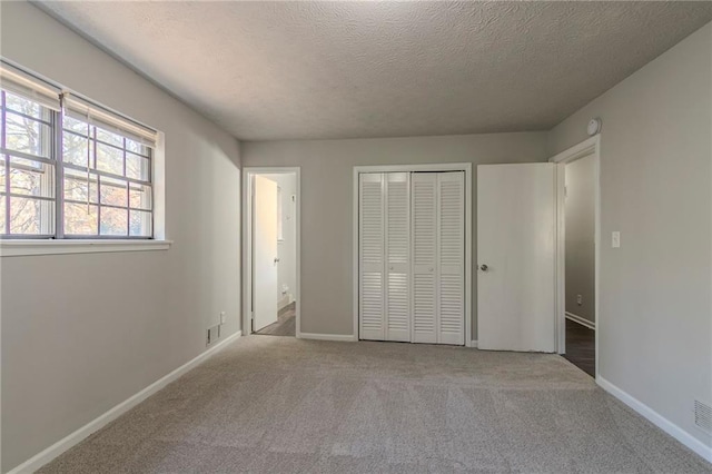 unfurnished bedroom featuring a closet, light carpet, and a textured ceiling