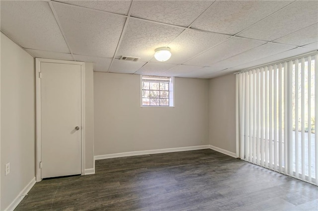 empty room with a paneled ceiling and dark hardwood / wood-style floors