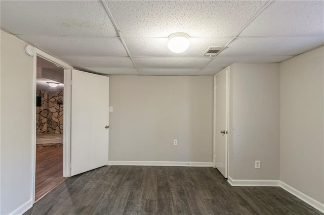 unfurnished room with a paneled ceiling and dark hardwood / wood-style flooring