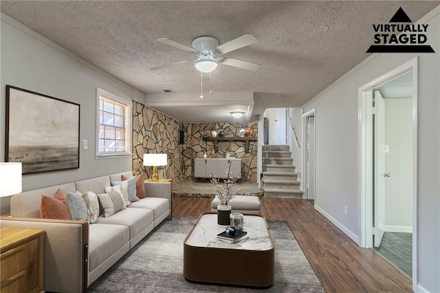 living room featuring hardwood / wood-style flooring, ceiling fan, a fireplace, and a textured ceiling