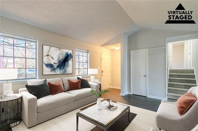 living room featuring a healthy amount of sunlight, vaulted ceiling, light hardwood / wood-style flooring, and a textured ceiling