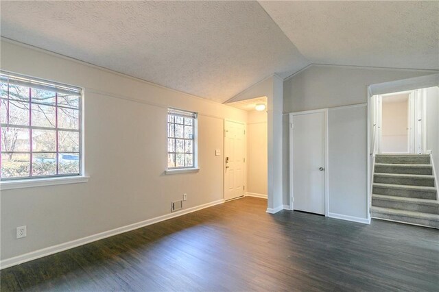 interior space with dark wood-type flooring, vaulted ceiling, and multiple windows