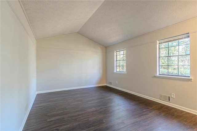 spare room featuring dark hardwood / wood-style floors, vaulted ceiling, and a textured ceiling