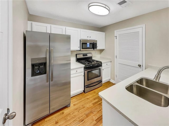 kitchen featuring white cabinetry, sink, light hardwood / wood-style floors, and appliances with stainless steel finishes