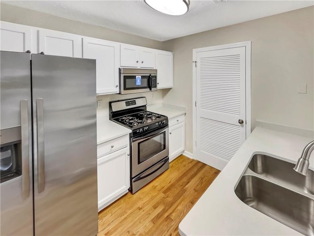 kitchen with light hardwood / wood-style floors, sink, white cabinetry, and stainless steel appliances