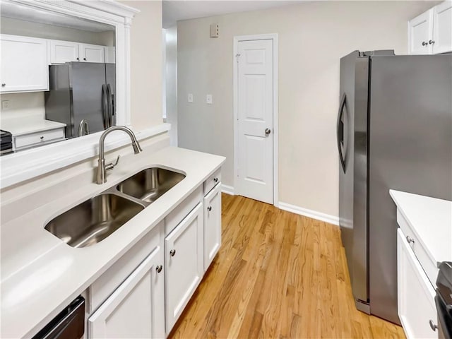 kitchen featuring white cabinets, light hardwood / wood-style flooring, stainless steel refrigerator, and sink