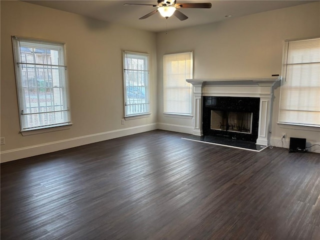 unfurnished living room with a fireplace, plenty of natural light, ceiling fan, and dark wood-type flooring