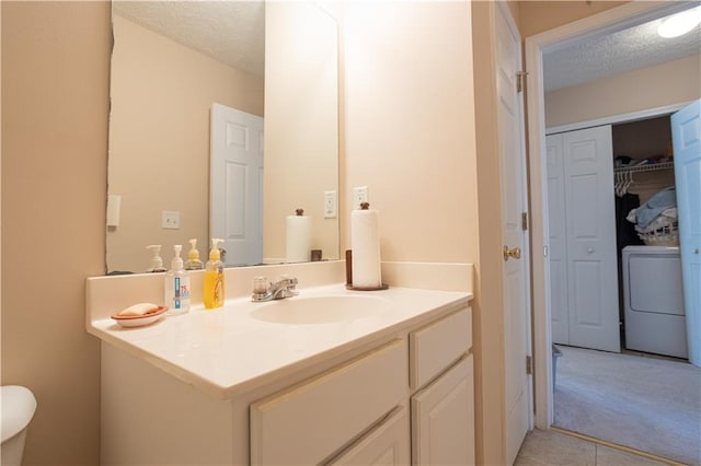 bathroom with washer / dryer, a closet, vanity, a textured ceiling, and tile patterned flooring