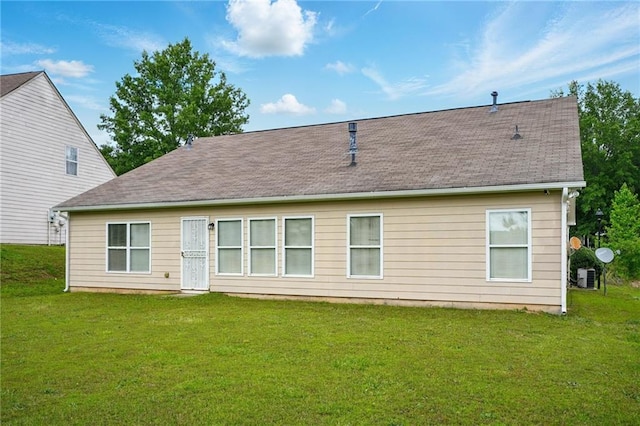rear view of property featuring a lawn, a shingled roof, and central air condition unit