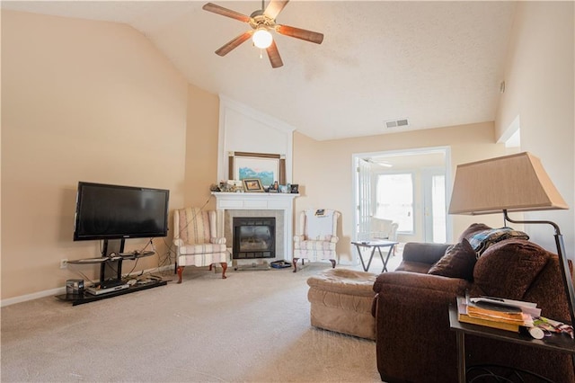 living room with a ceiling fan, lofted ceiling, carpet flooring, a tiled fireplace, and baseboards