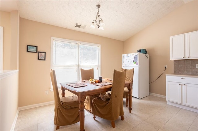 dining room with a textured ceiling, light tile patterned floors, baseboards, lofted ceiling, and a chandelier